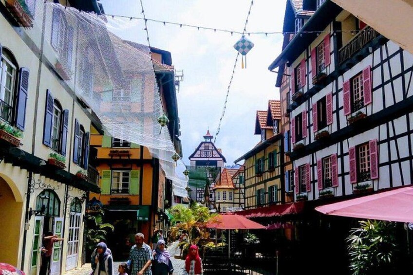 A narrow street with colorful half-timbered buildings, string lights, and people walking. 5