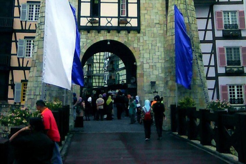 A pedestrian bridge with stone walls and flags, leading to a building with a large archway. 3