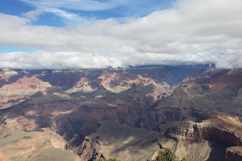 A vast canyon landscape with layered rock formations and a cloudy sky. 3