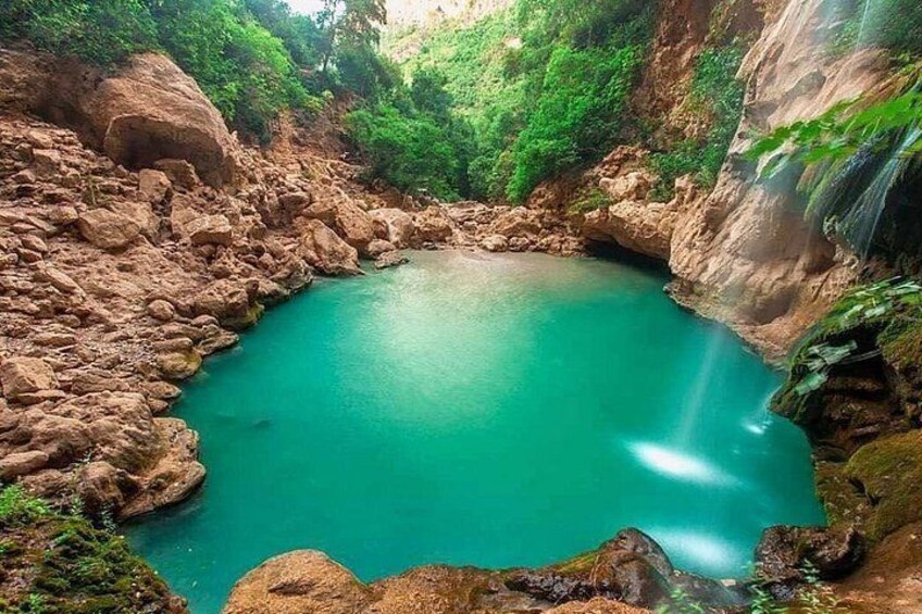 A turquoise pool surrounded by rocky terrain and greenery. 3