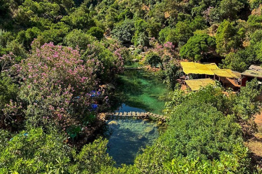 A river with a wooden bridge, surrounded by lush greenery and a yellow-roofed structure. 2