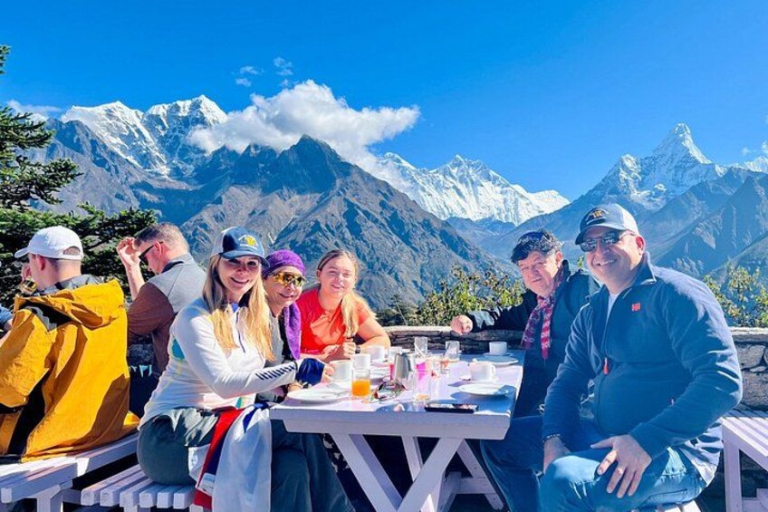 Un groupe de personnes est assis autour d’une table, avec une montagne en toile de fond. 1