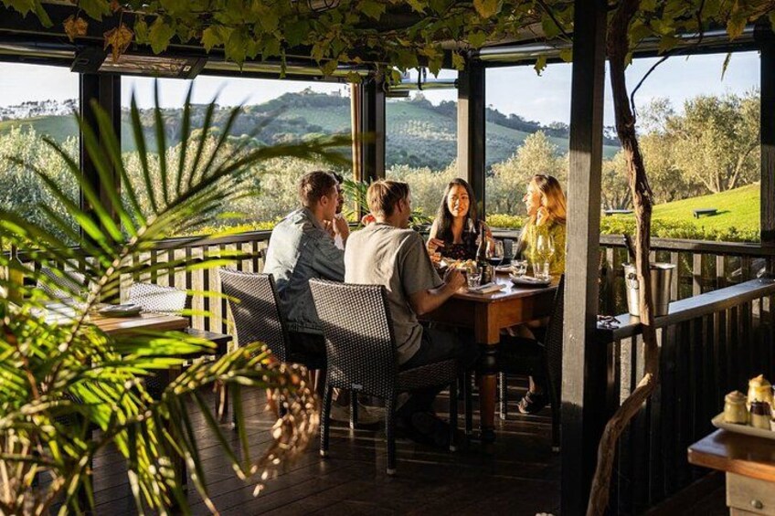 A group of people dining at an outdoor table with a view of the countryside. 2