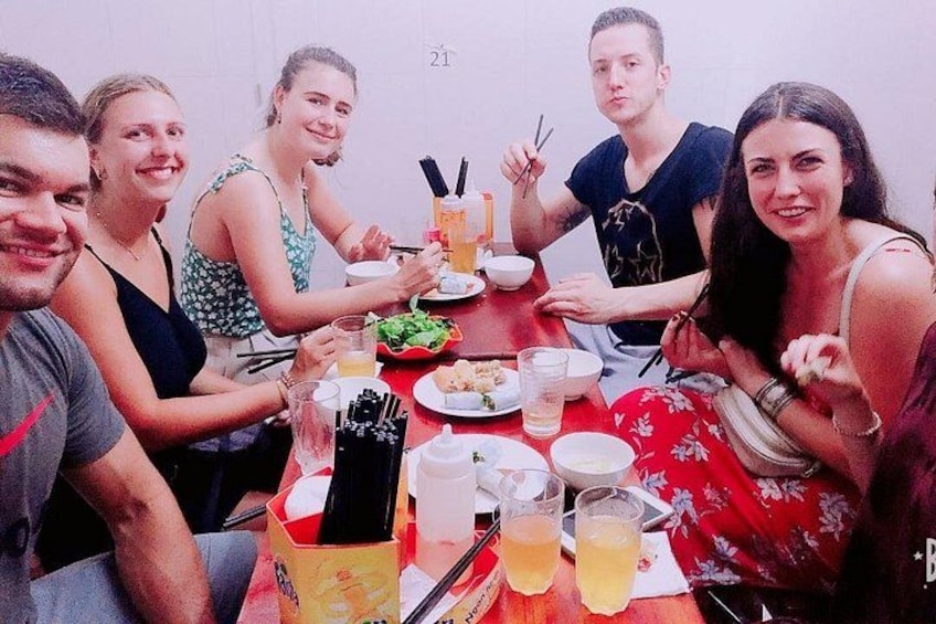 A group of people dining at a table with various dishes and drinks. 1