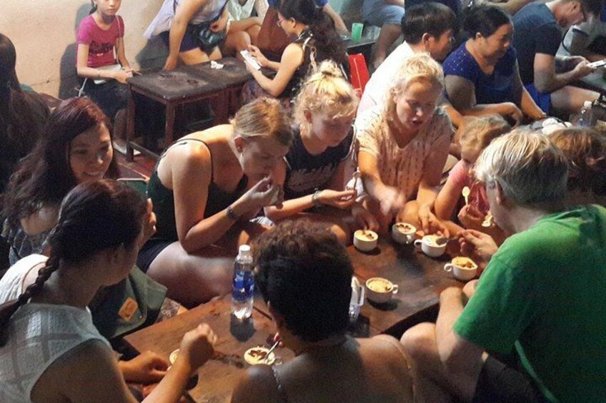 A group of people sitting around a table, eating and drinking. 2