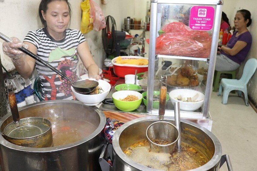 A street food vendor preparing food with large pots and bowls. 3