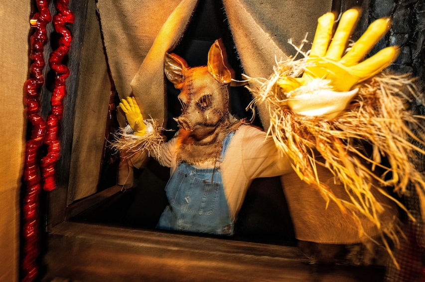 A scarecrow with a yellow hand and a red garland. 5