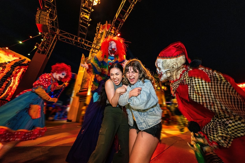 A nighttime amusement park with a Ferris wheel, a clown, and a Santa Claus figure. 1