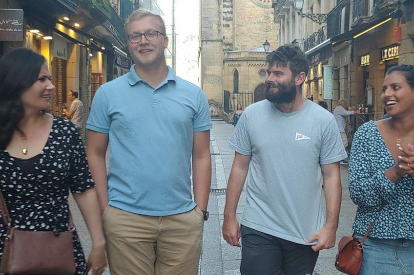 A group of people standing on a street with buildings and shops in the background. 3