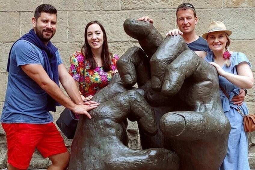 Een groep mensen poseert met een bronzen beeldhouwing van verstrengelde mensenfiguren. 4