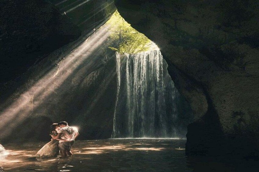A waterfall inside a cave with sunlight streaming through an opening. 4