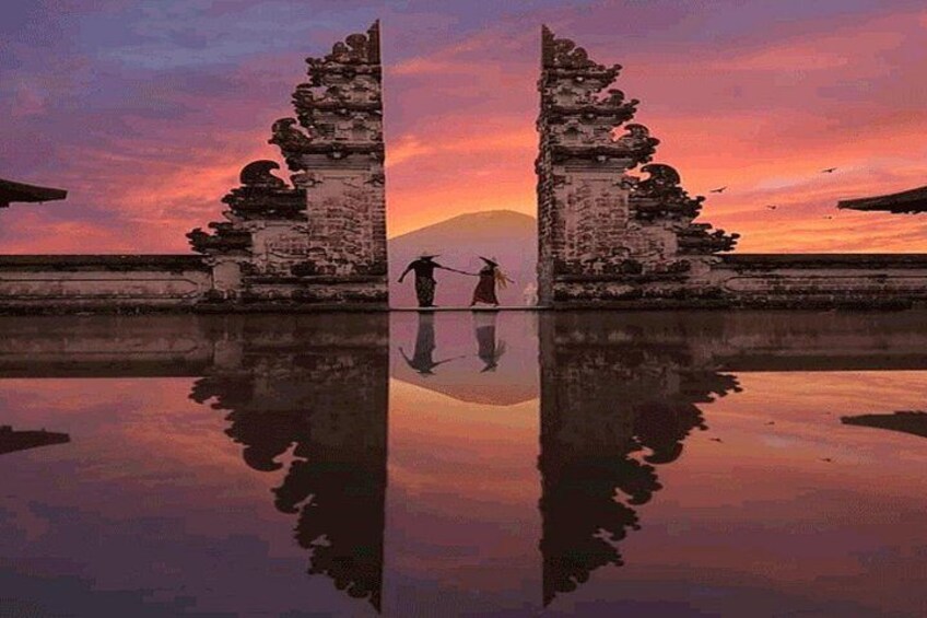 A temple with a reflection in the water, a person standing in the middle, and a sunset in the background. 1