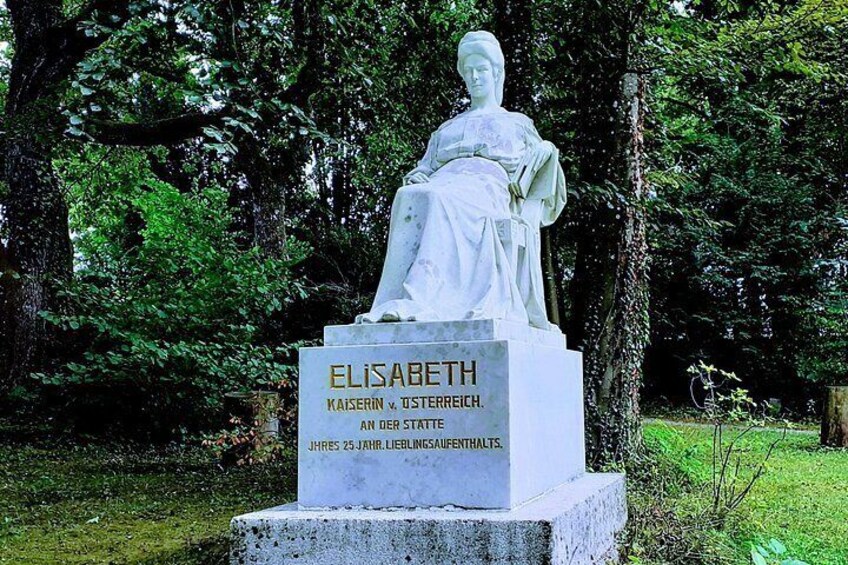 A statue of Elisabeth in a park with trees and a plaque. 5