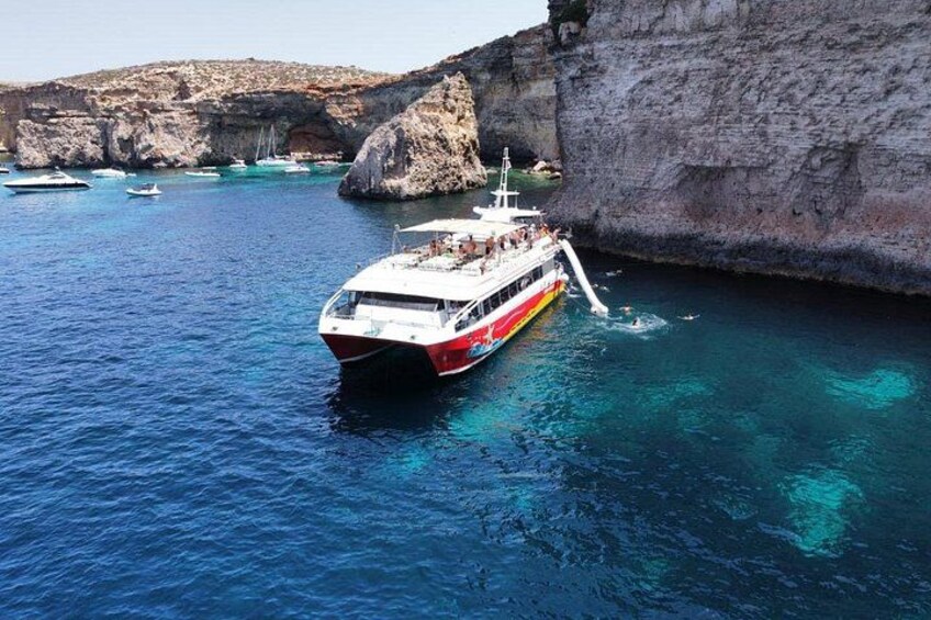 A boat anchored near a rocky coastline with clear blue water. 3