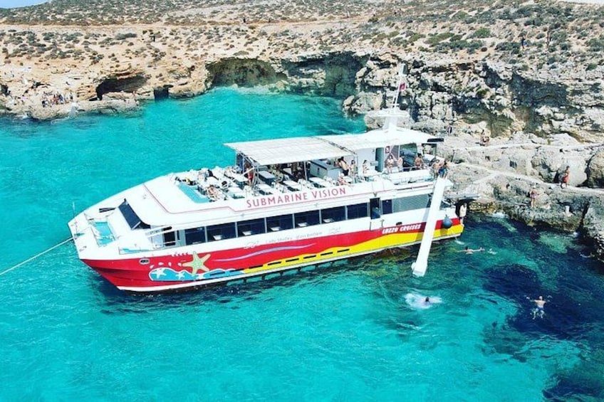 A boat named 'Submarine Vision' with passengers, floating near rocky cliffs in clear turquoise water. 3