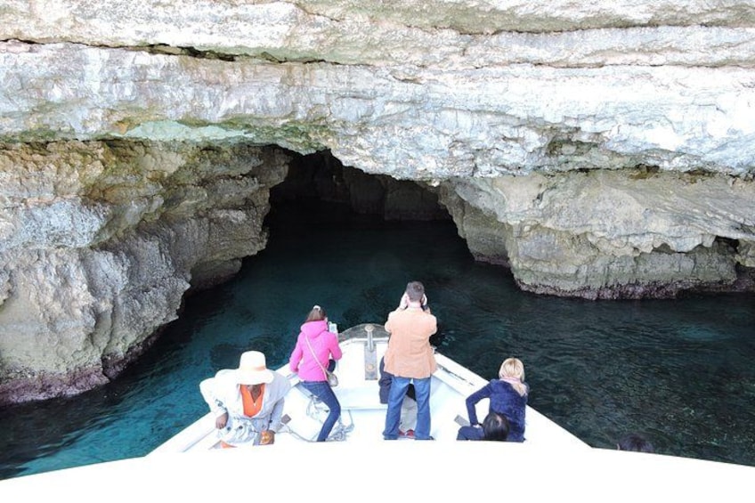 A boat with people near a rocky cave entrance. 4