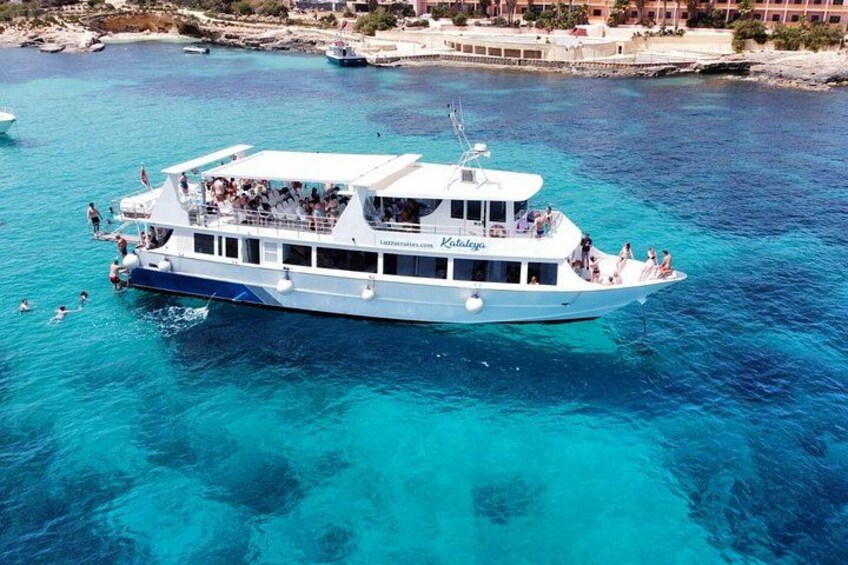 A white boat with people on board, floating on clear blue water. 2