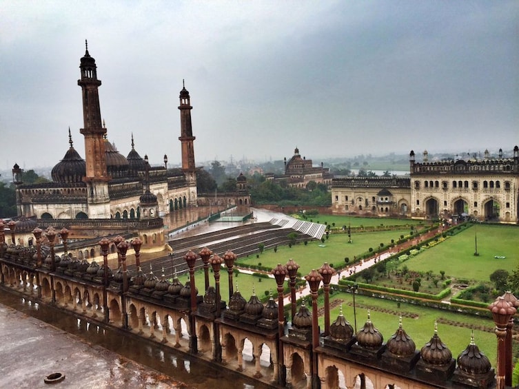 A large historical building with domes and minarets, surrounded by a well-maintained garden and a long, ornate bridge. 1