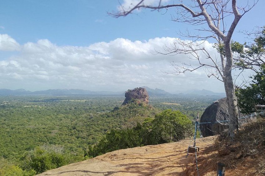 A mountainous landscape with a prominent rock formation, a clear sky, and a tree in the foreground. 2