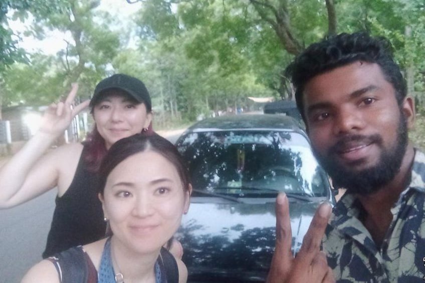 Three people posing in front of a car with trees in the background. 4