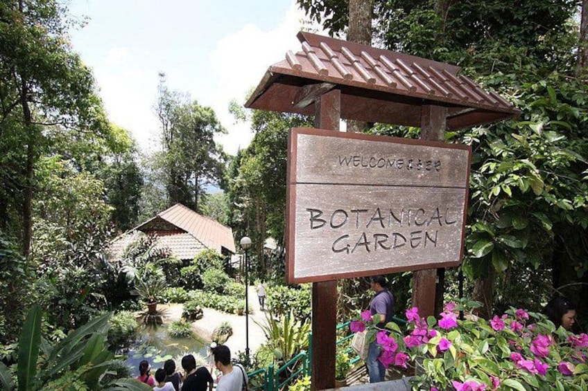 A sign for a botanical garden with lush greenery and a pond. 3