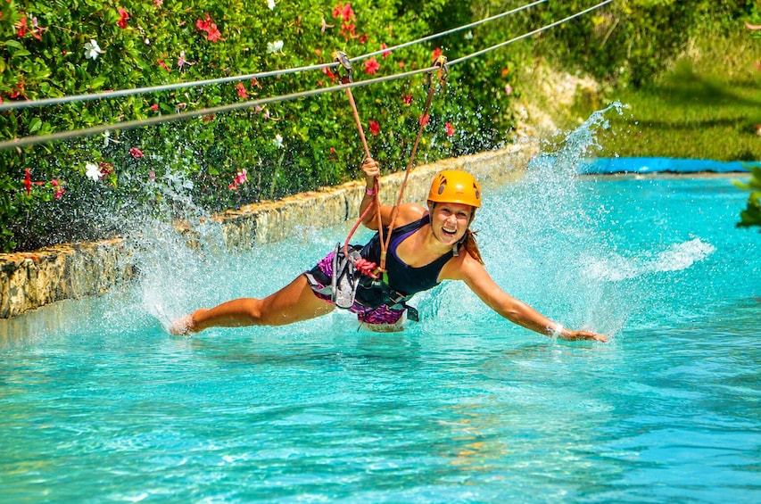 A person water skiing on a clear blue pool with a rope. 5