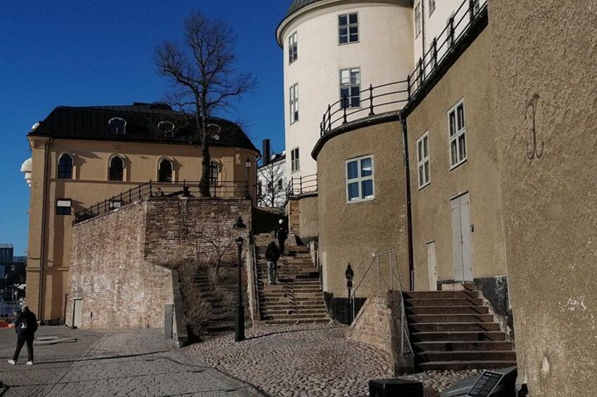 Une rue pavée, avec un escalier en pierre menant à un bâtiment doté de fenêtres en arc de cercle. 4