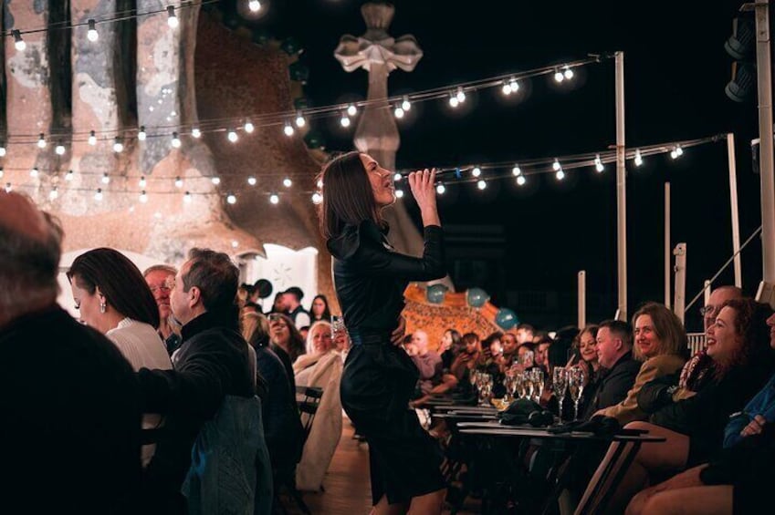 A crowded outdoor event with string lights and tables. 1