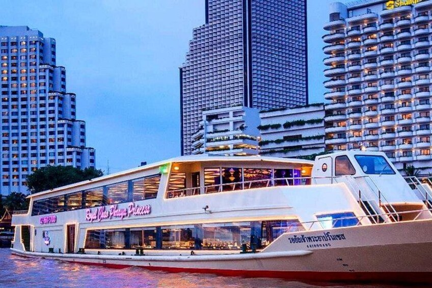 A white boat with a restaurant named 'By the Sea Princess' on a body of water with city buildings in the background. 2