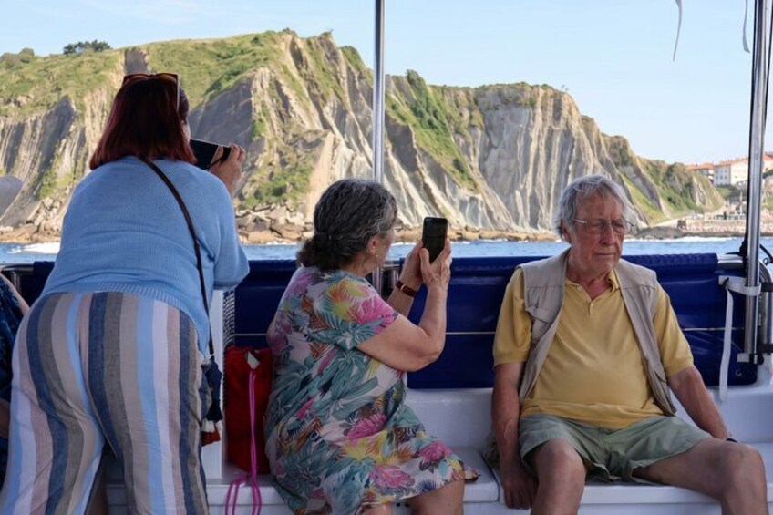 People on a boat with a rocky coastline in the background. 2