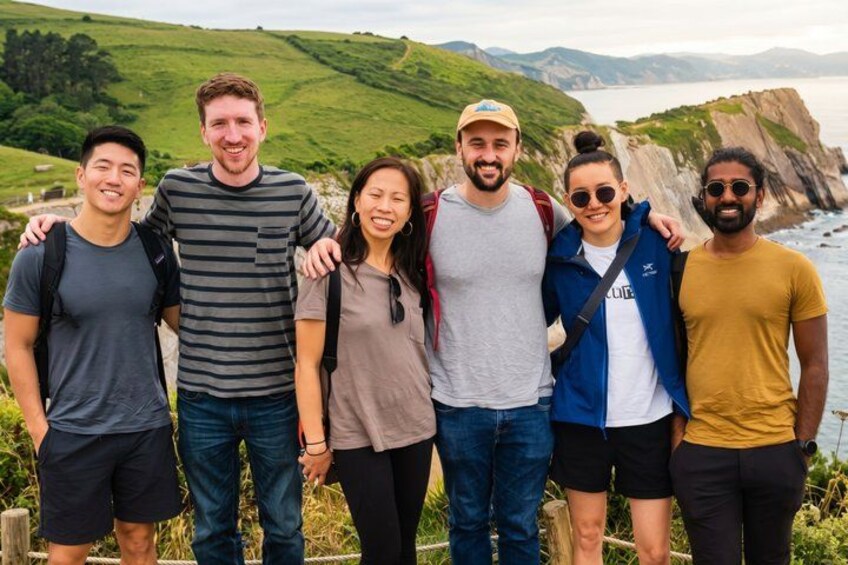A group of people standing on a grassy hill with a coastal landscape in the background. 1