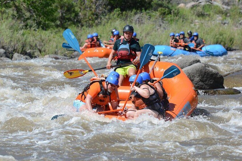 A group of people rafting down a river in an orange raft. 3
