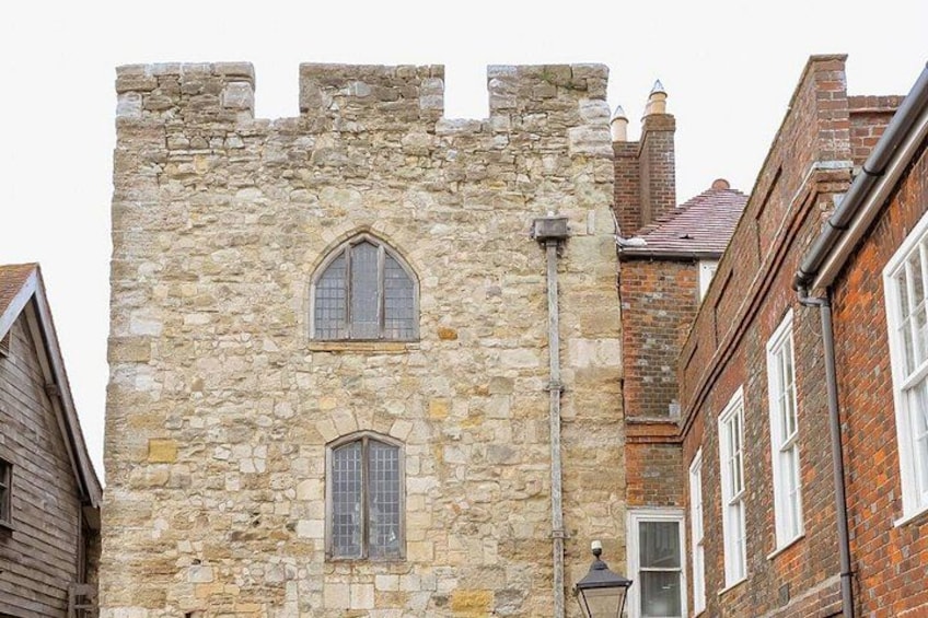 A stone tower with arched windows and a brick building with white windows. 3
