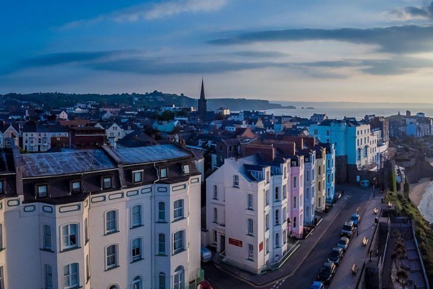 A coastal town with colorful buildings, a prominent church spire, and a road leading to the beach. 2