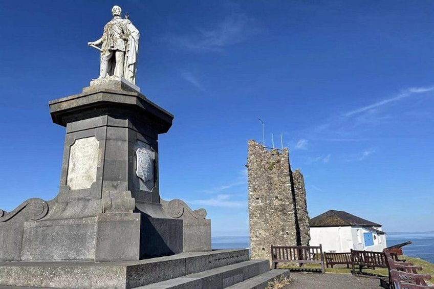 A statue on a pedestal, a stone tower, and a small white building with a blue door. 5
