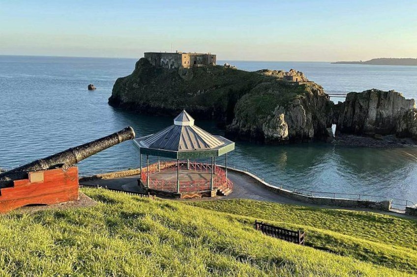 A coastal fortification with a large cannon, a gazebo, and a castle on a cliff. 4