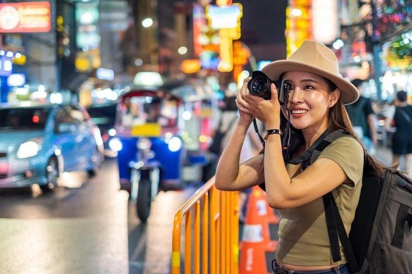 Eine Person macht nachts auf einer belebten Straße in der Stadt ein Foto mit einer Kamera. 2
