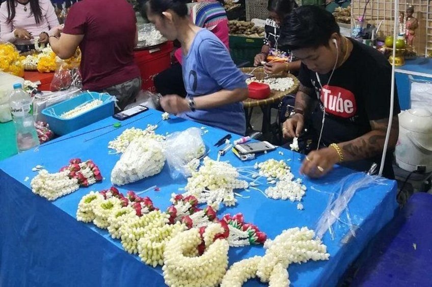 A market stall with people preparing flower garlands. 4