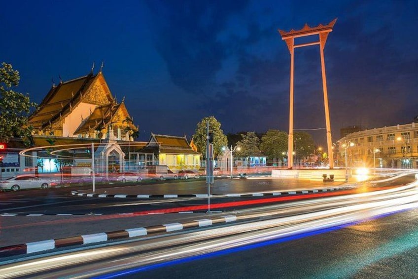 A night scene with a traditional building, a tall structure, and a busy road with light trails. 2