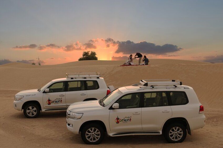 Two white SUVs with 'Orient' branding parked on a desert sand dune. 4
