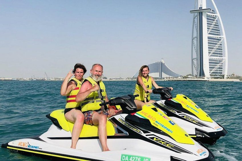 Two jet skis on the water with a sailbridge in the background. 2