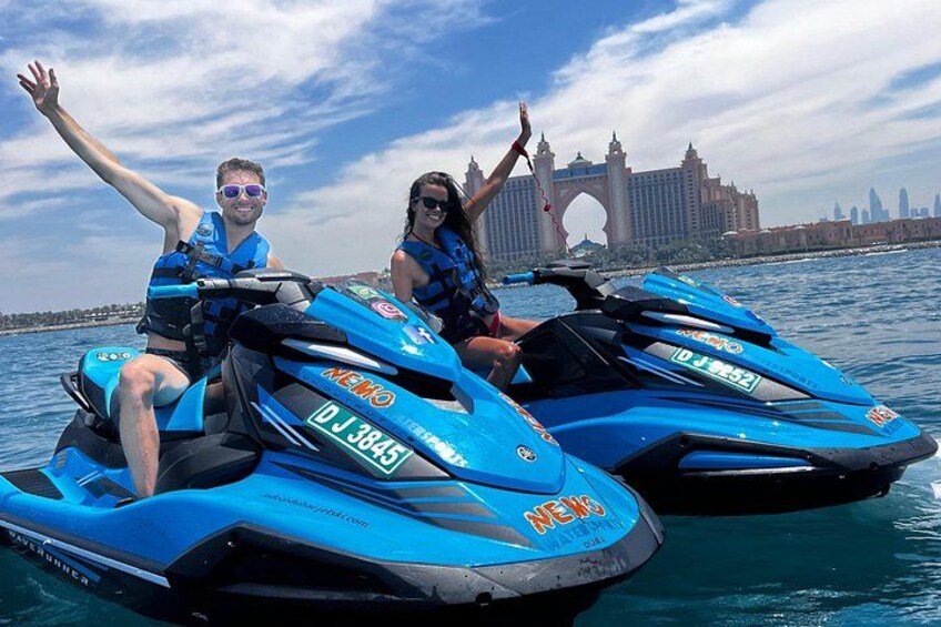 Two jet skis on water with a city skyline in the background. 2