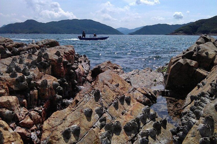 Eine felsige Küstenlinie mit einem Boot auf dem Wasser und Bergen im Hintergrund. 3