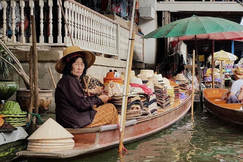 Una donna in barca con un cappello grande, circondata da altre imbarcazioni e ombrelli, a indicare un canale trafficato. 4