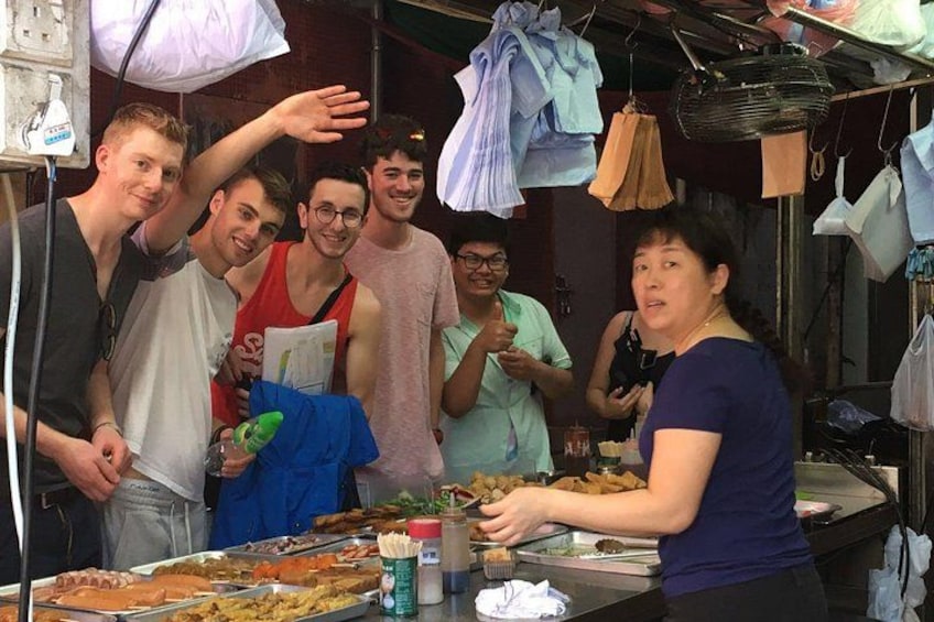 Un groupe de personnes se trouve devant un étal de nourriture où sont proposés différents plats, et une femme y sert des aliments. 1