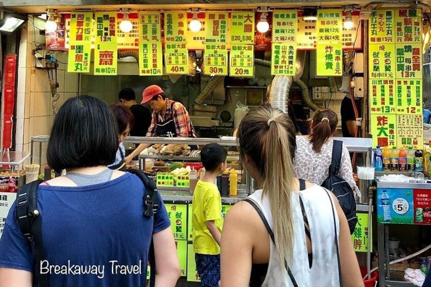 A street food stall with people queuing and a vendor preparing food. 2