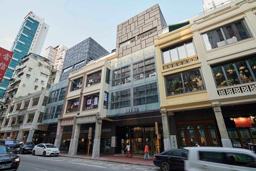 A street with multi-story buildings, storefronts, and vehicles. 4