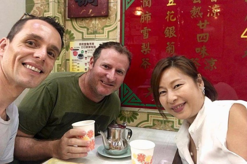 Three people sitting at a table with cups and a teapot. 5