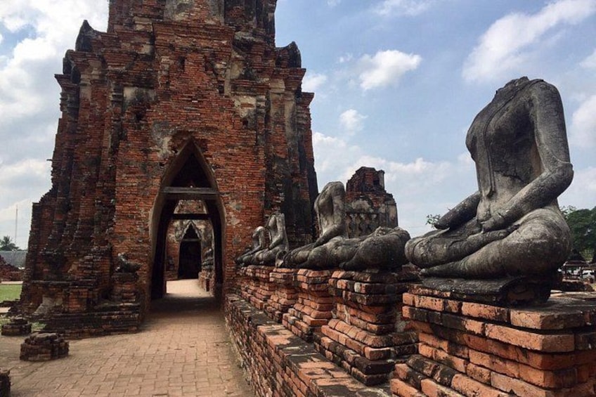 A temple with a brick entrance, large stone Buddha statues, and a clear sky. 1