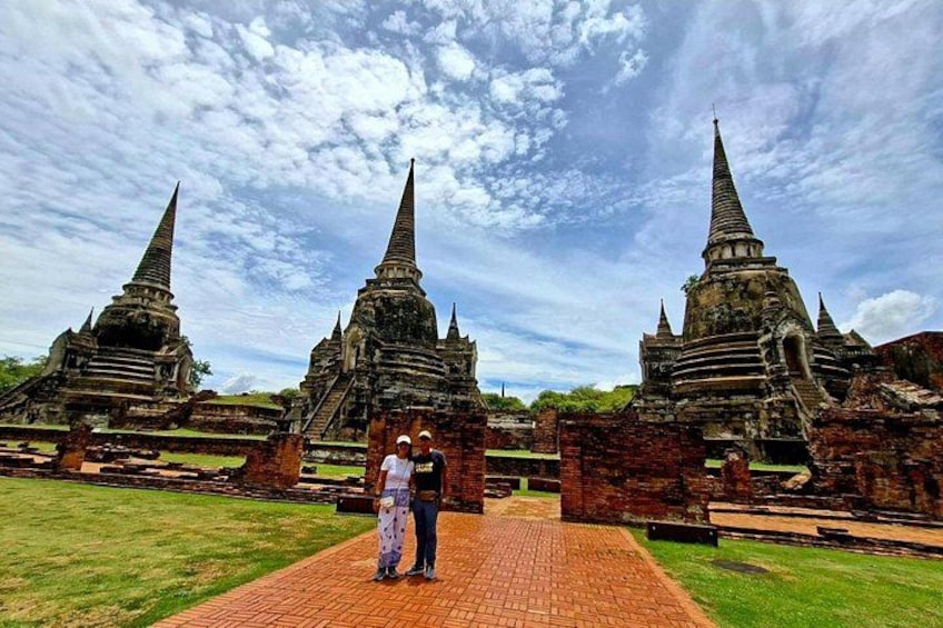 Ancient temple ruins with multiple spires, a paved pathway, and a grassy area. 3